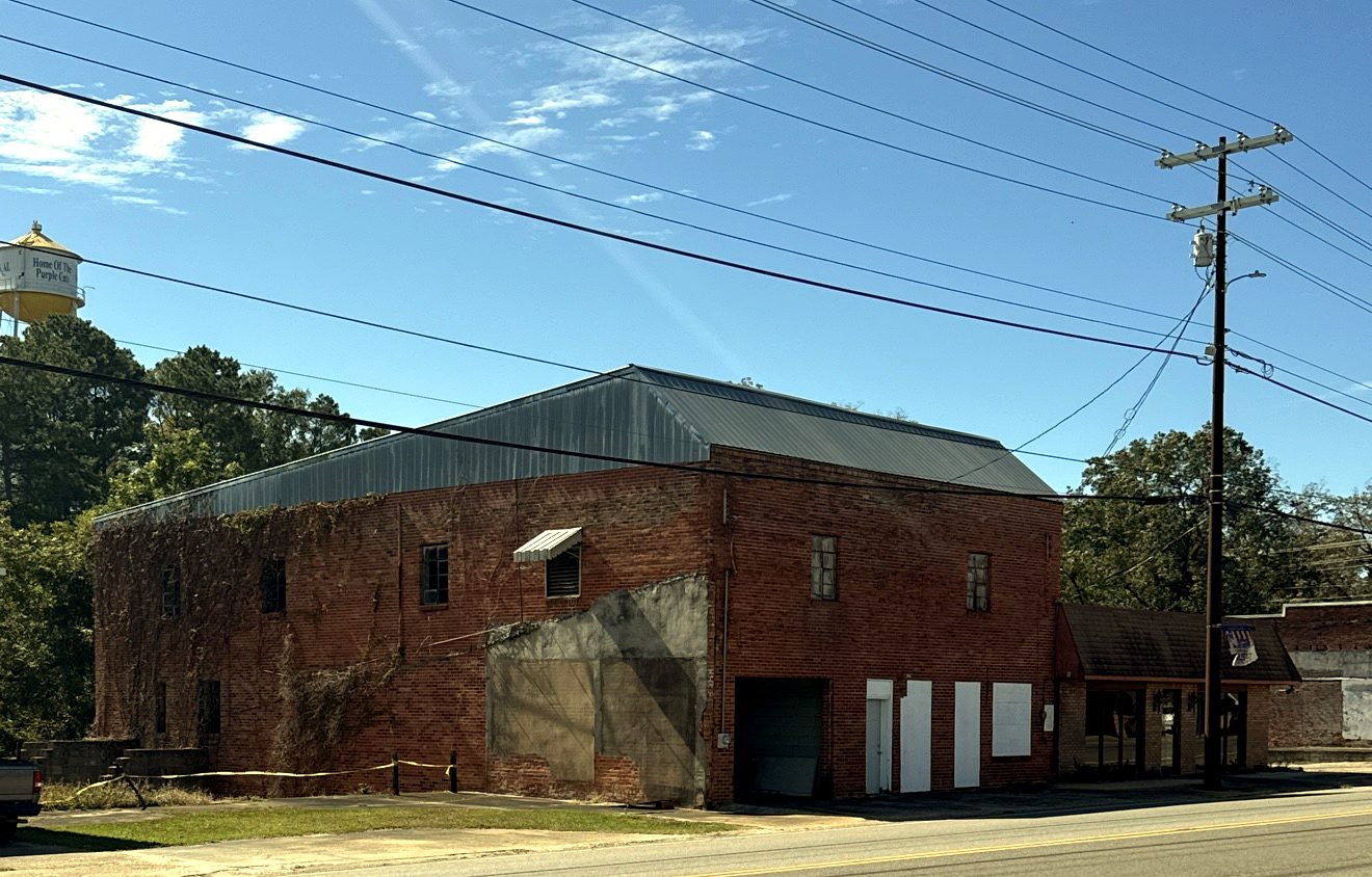 Historic red-brick building on Main Street in Ariton, with the water tower beyond